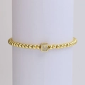 Elastic beaded bracelet in 18k gold finish featuring a cubic charm with letter M - Letter M