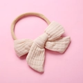 Detail of baby muslin headband with soft beige cotton bow on elastic nylon band - Off-white