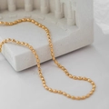 Detail of a minimalist gold oval bead chain necklace draped on a white prop - Gold Oval Bead Chain