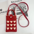 Detail of red knitted crossbody bag with white heart patterns and silver metal snap button - Red Heart