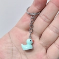 Light blue resin duck keychain pendant on metal ring held in palm for size reference - 25mm Ring / Blue