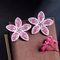 Close-up of pink and white zircon flower earrings on brown silk jewelry box - Red