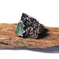 Détail d'une bague en bronze faite main avec pierre verte brute sur fond d'écorce - Fluorite Verte