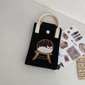 Dettaglio borsa porta cellulare in maglia con gatto, manici bianchi e oggetti di scena magazine - Gatto Nero su Sgabello