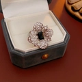 Makroaufnahme von silbernem Blumenring mit schwarzem Edelstein in grauer Box - Silber Schwarz Ring