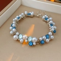 Dettaglio macro di un bracciale vintage con perle e opale blu in una scatola beige - Bracciale-Blu