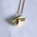 Detailed close-up of a 3D polished golden letter K pendant with a shiny bubble design - Letter K