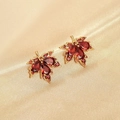 Detail of maple leaf stud earrings with red pear-cut gems on champagne silk fabric - E2975 Maple Leaf Red / Red