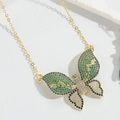 Macro shot of gold butterfly pendant with colorful zircons on a textured white surface - Gold Butterfly (Colorful Zirconia)