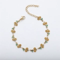 Detailed close-up of 18k gold-plated cherry bracelet with green enamel and lobster clasp - Gold+Yellow