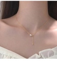 Detail of gold Y-shaped necklace featuring a white pearl and delicate fine chain on collarbone - Pearl Cylinder Necklace-Gold Color