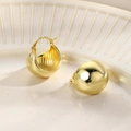 Dettaglio di orecchini a cerchio dorati lucidi a goccia su un vassoio di ceramica beige - Oro Cerchio con Sfera Grande