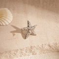 Detailed view of a silver starfish ear clip on a stone surface with a seashell background - Clip Earring - Silver Spiral Starfish