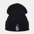 Close-up of white skeleton hand embroidery on a black ribbed knit beanie hat - Black