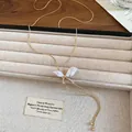 Collana con ciondolo a farfalla in madreperla e catena d'oro in una scatola di gioielli - Violazione Del Copyright Dello Sfondo - {miu Miu} / Oro