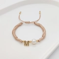 Detail of handmade champagne woven bracelet with letter M gold charm and white pearl - Letter M