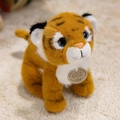 Adorable orange tiger plush toy with black stripes and blue eyes sitting on white rug - Yellow Tiger