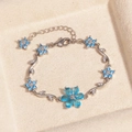 Silbernes Blumenarmband mit blauen und weißen Kristallen auf beigem Displaypad - Blume Blauer Zirkon Platin