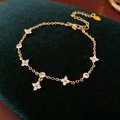 Macro shot of gold-plated flower bracelet with zircon stones on green velvet background - Gold