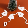 Detail of four white TPR sticky Santa Claus toys with curved hooks on orange background - White Santa
