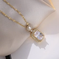 Detailed close-up of golden necklace with rectangular zircon pendant on beige silk - White Zirconia Necklace