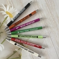 Set of 7 glitter ballpoint pens with weekday themes on a light wood background - Halloween 7-Piece Set