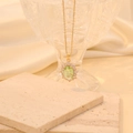 Close-up of gold stainless steel necklace featuring a green oval crystal pendant with diamonds - Light Green