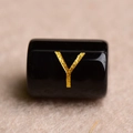 Macro shot of a black cylindrical bead with a golden letter Y for DIY jewelry making - Letter Y