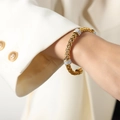 Golden woven cable cuff bracelet with sparkling pavé diamond bands on a model's wrist - Gold
