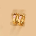 Dettaglio di orecchini a cerchio dorati con croci rosa su uno sfondo beige neutro - Rosa