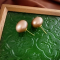 Primer plano de pendientes de perlas champán con agujas doradas en bandeja retro - Marrón