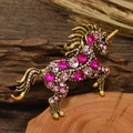 Vintage gold unicorn brooch pin with pink rhinestones on a rustic wood background - Pink