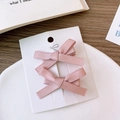 Gros plan de barrettes à nœuds en satin rose sur carte pour coiffure style ballet - Rose