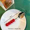 Cuillère moderne 18 cm en inox avec manche créatif en perles rouges sur assiette - Cuillère / Rouge