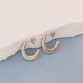 Detailed macro view of silver C-shape earrings with textured honeycomb pattern on white stone - Silver Honeycomb Etched Buckle