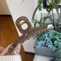 Close-up of a glossy brown oversized butterfly hair claw with a gold metal spring - Transparent Brown