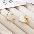 Detail of heart-shaped white enamel earrings with gold edges on beige fabric - Cream