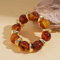 Macro shot of amber resin beads with irregular metallic spacers on a stone background - Amber Style / Brown