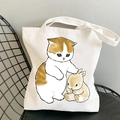White canvas tote bag featuring cute orange cat and rabbit cartoon print on a chair - Cat and Rabbit