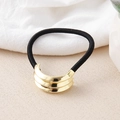 Macro view of elastic hair tie featuring a golden metal knot detail on a neutral fabric - Gold Three-Stripes Intercept
