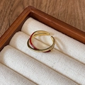 Detail of a golden double-loop ring with vibrant red enamel on a luxury jewelry cushion - Style 7 Ring-Gold-Red-Double Layer Cross
