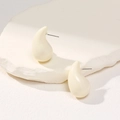 Detailed macro view of cream teardrop earrings on a white minimalist stone base - Cream