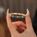 Close-up van gouden armband met regenboog zirkonia in een verfijnde klauwzetting - Kleurrijk