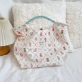 Detail of cartoon printed tote bag with cream wavy fabric and blue woven handles - Lace Pastry