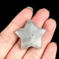 Natural star-shaped gray labradorite stone held on fingertips for size comparison - Labradorite