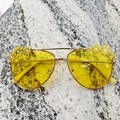 Close-up of yellow lens sunglasses with golden frame and daisy flower details - Yellow