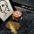 Round scented candle in bohemian floral metal tin on luxury grey plush carpet - H17 Cinnamon