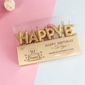 Macro shot of gold Happy Birthday letter candles in a transparent gift box set - Gold
