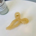 Detailed view of a beige translucent bow-shaped hair claw clip on a clean white desk - Jelly Apricot