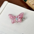 Barrette papillon en marbre rose avec strass brillants posée sur un livre ancien - Barrette / Rose